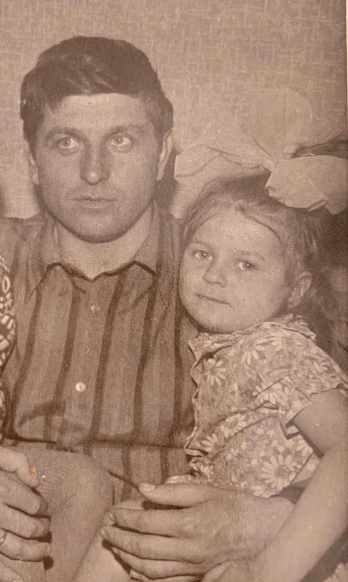 Oksana Koriakova as a little girl sitting on her dad's lap